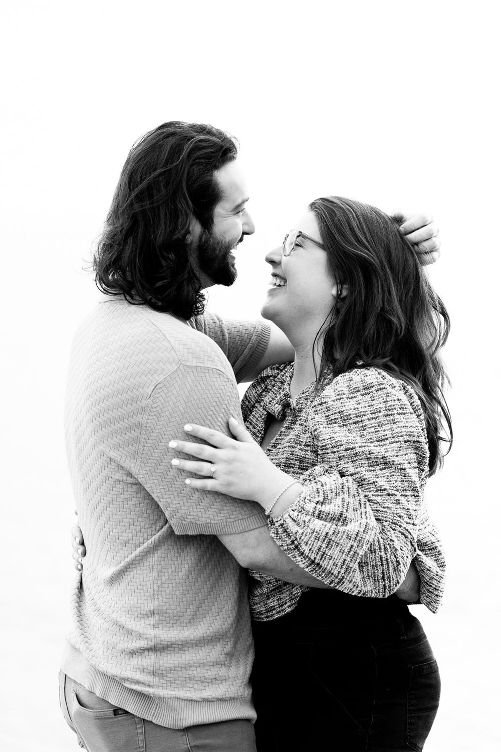 Black and white photo of a happy couple embracing and laughing together outdoors.