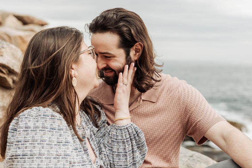 A couple sharing a tender romantic moment with woman touching mans face by the ocean.