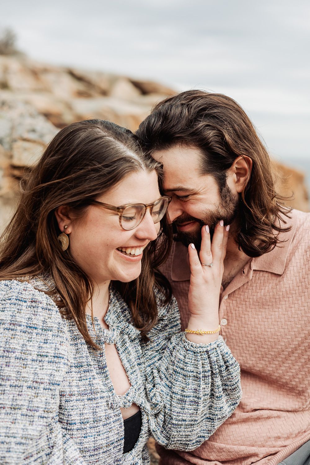 A laughing couple sharing an intimate moment, woman touching mans bearded face.