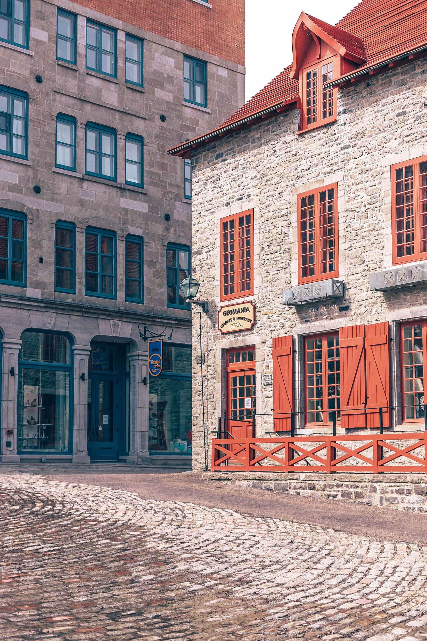 Historic stone building with red shutters and cobblestone street in Quebec's old town architecture.