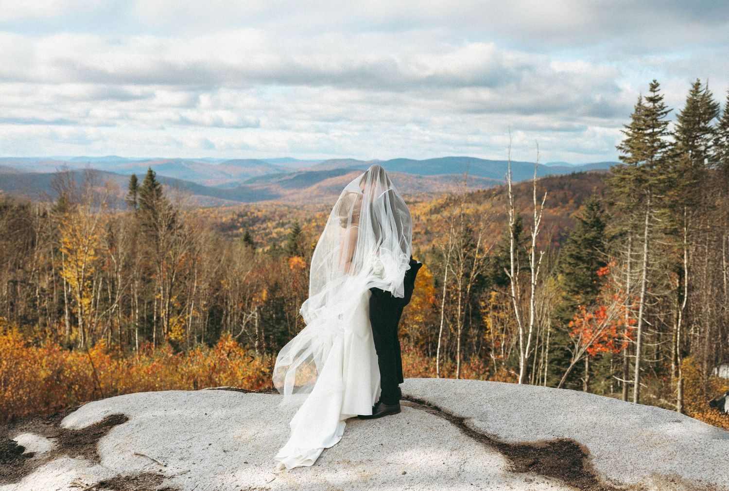 A scenic mountain wedding ceremony in autumn with stunning fall foliage and distant peaks in the background.
