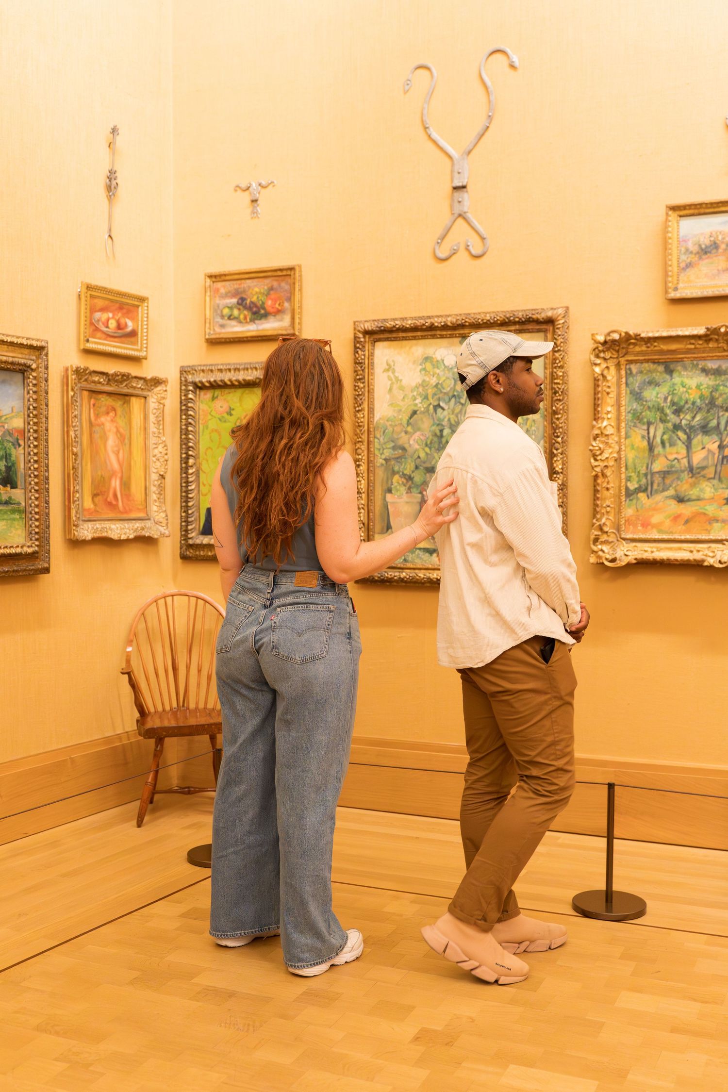 Couple viewing Impressionist paintings in a golden-walled art museum gallery.