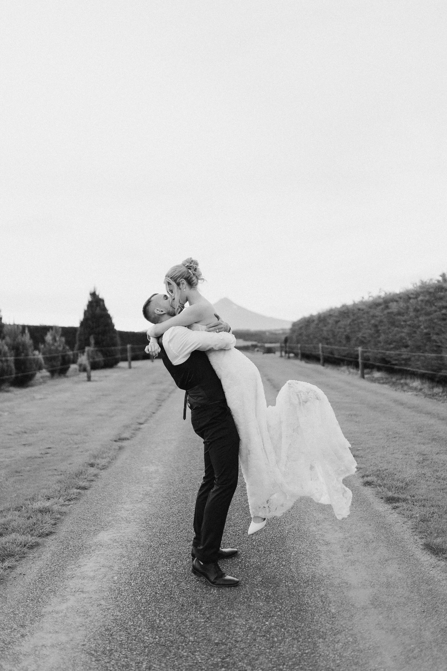 Husband and wife kiss in front of Mount Taranaki