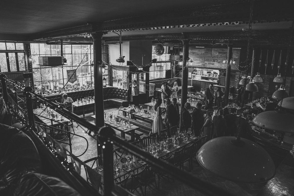 Black and white aerial view of elegant wedding reception in industrial-style venue with ornate decor.