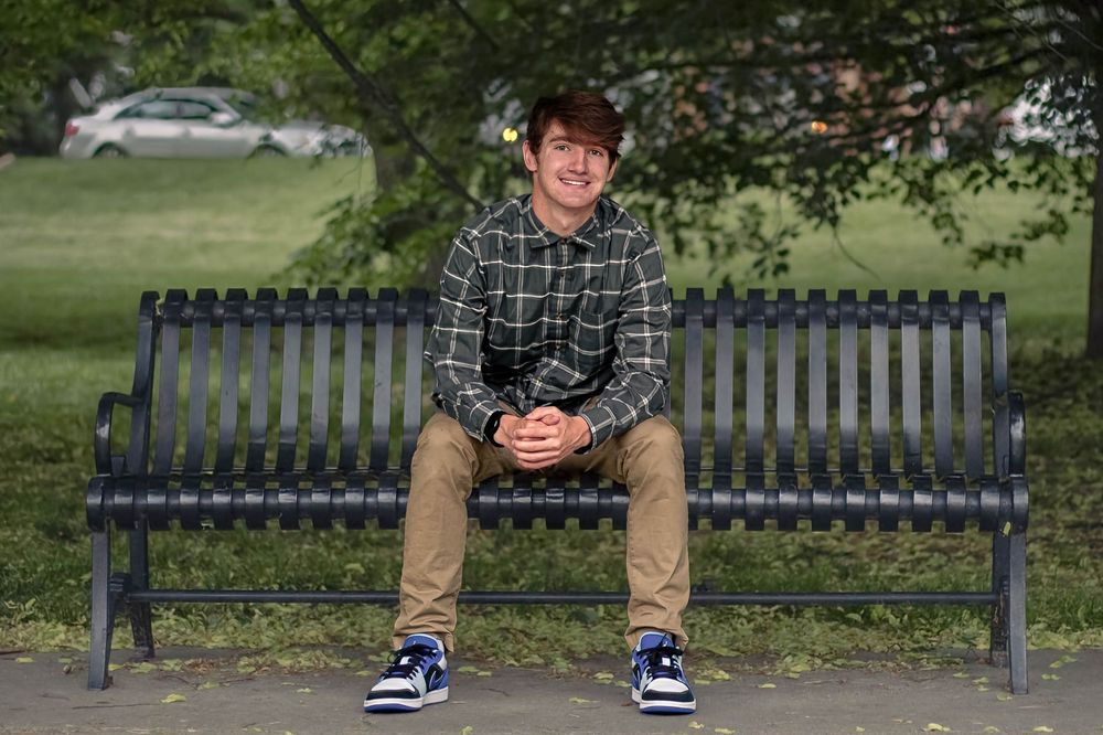 Senior photo in Kansas City with greenery in the background while the senior sits on a bench.