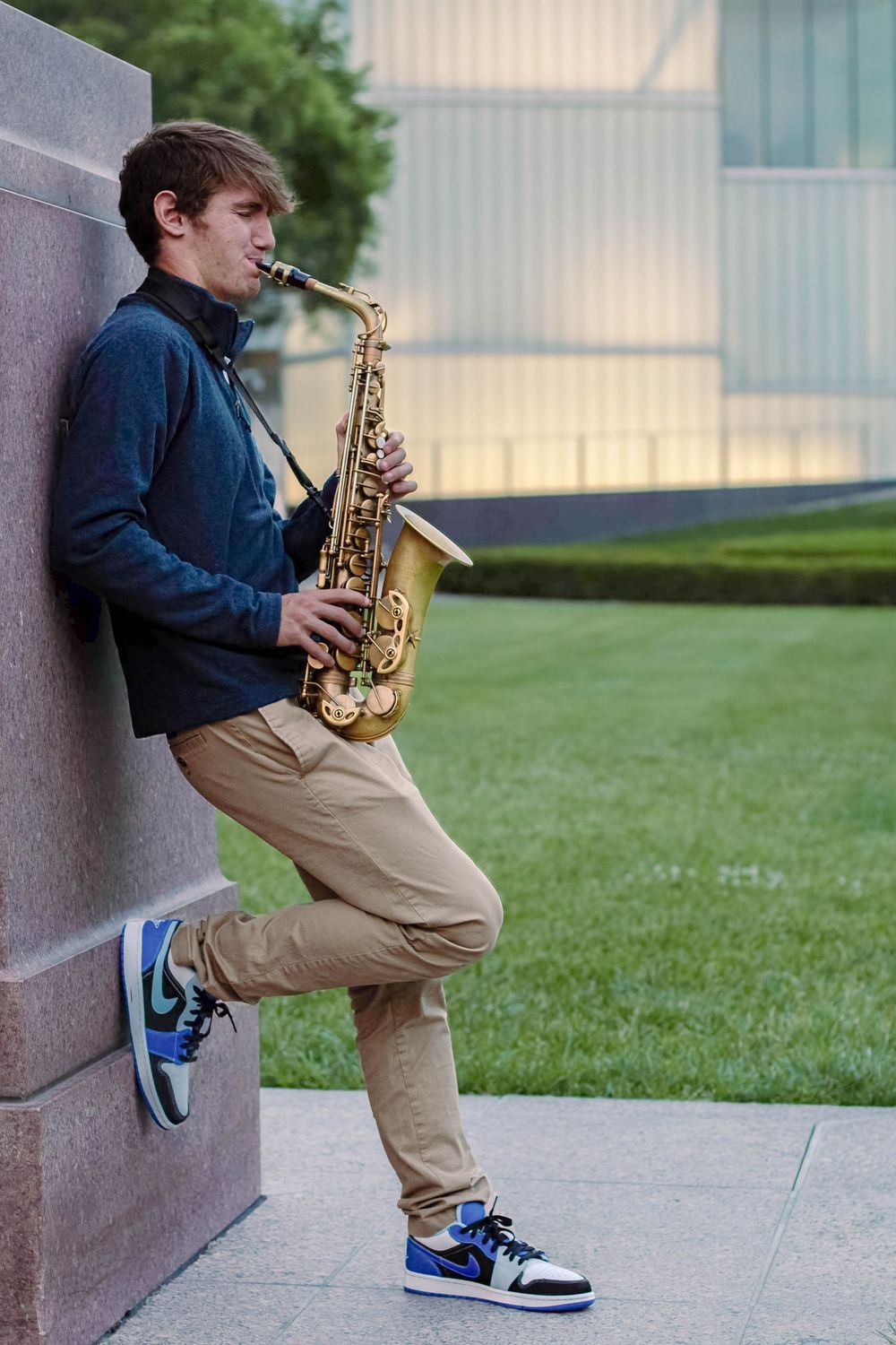 Senior photo in Kansas City at sunset with his saxophone and the city in the background.