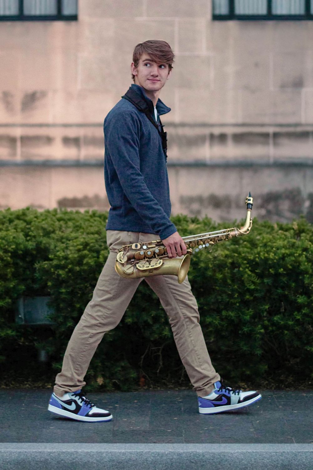 Senior photo in Kansas City at golden hour while walking with saxophone.