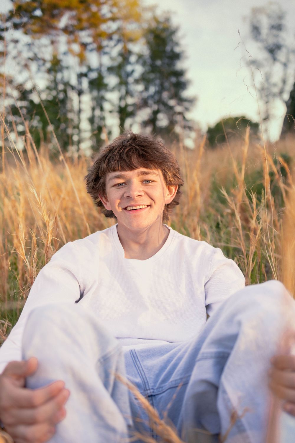 Senior photo in Charlottesville, VA at golden hour in tall grass.