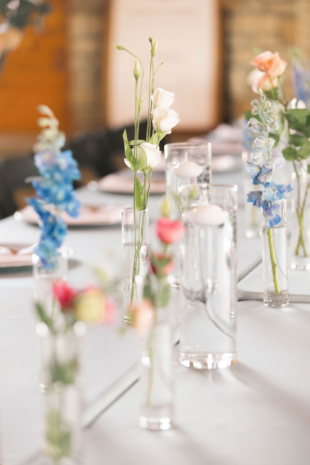 Delicate wedding reception table decor featuring single stem flowers in glass bud vases on white linen. bell manor Chillicothe ohio.