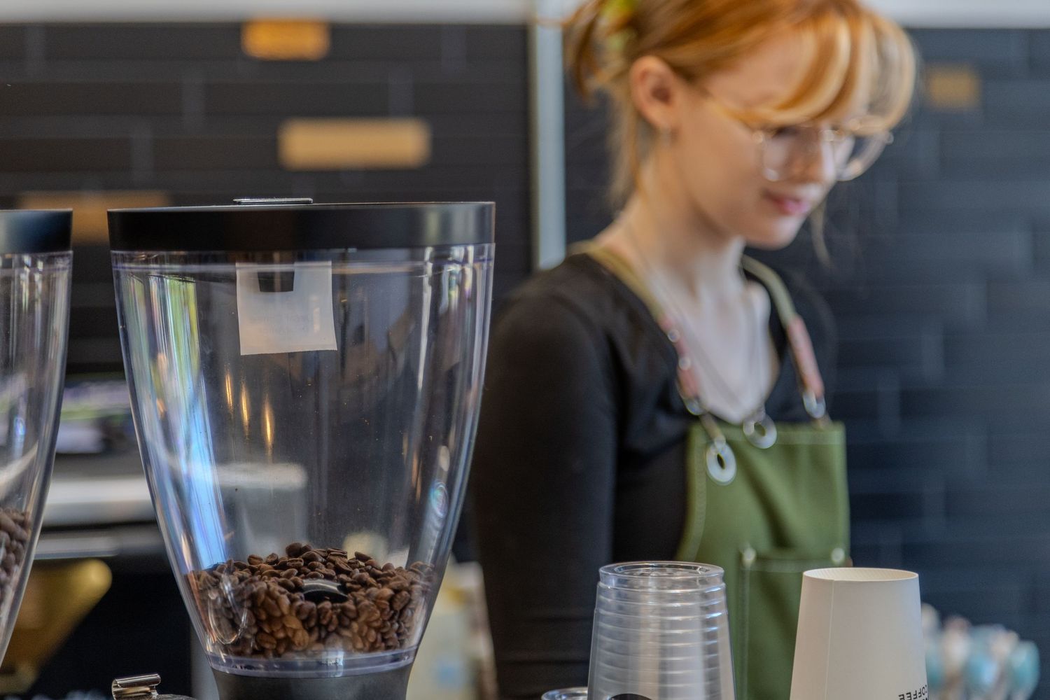 A barista pours steamed milk into a coffee cup creating latte art at a modern coffee shop counter.