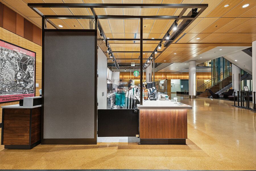 Modern retail lobby interior with wood accents, display cases, and industrial ceiling grid lighting.