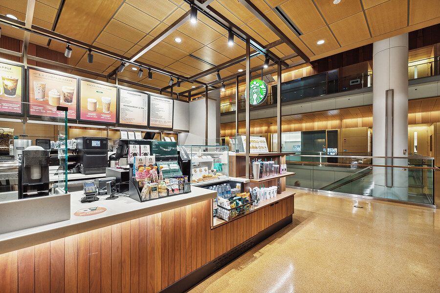 Starbucks coffee bar interior featuring espresso machines, menu boards, and wood-paneled counter display.