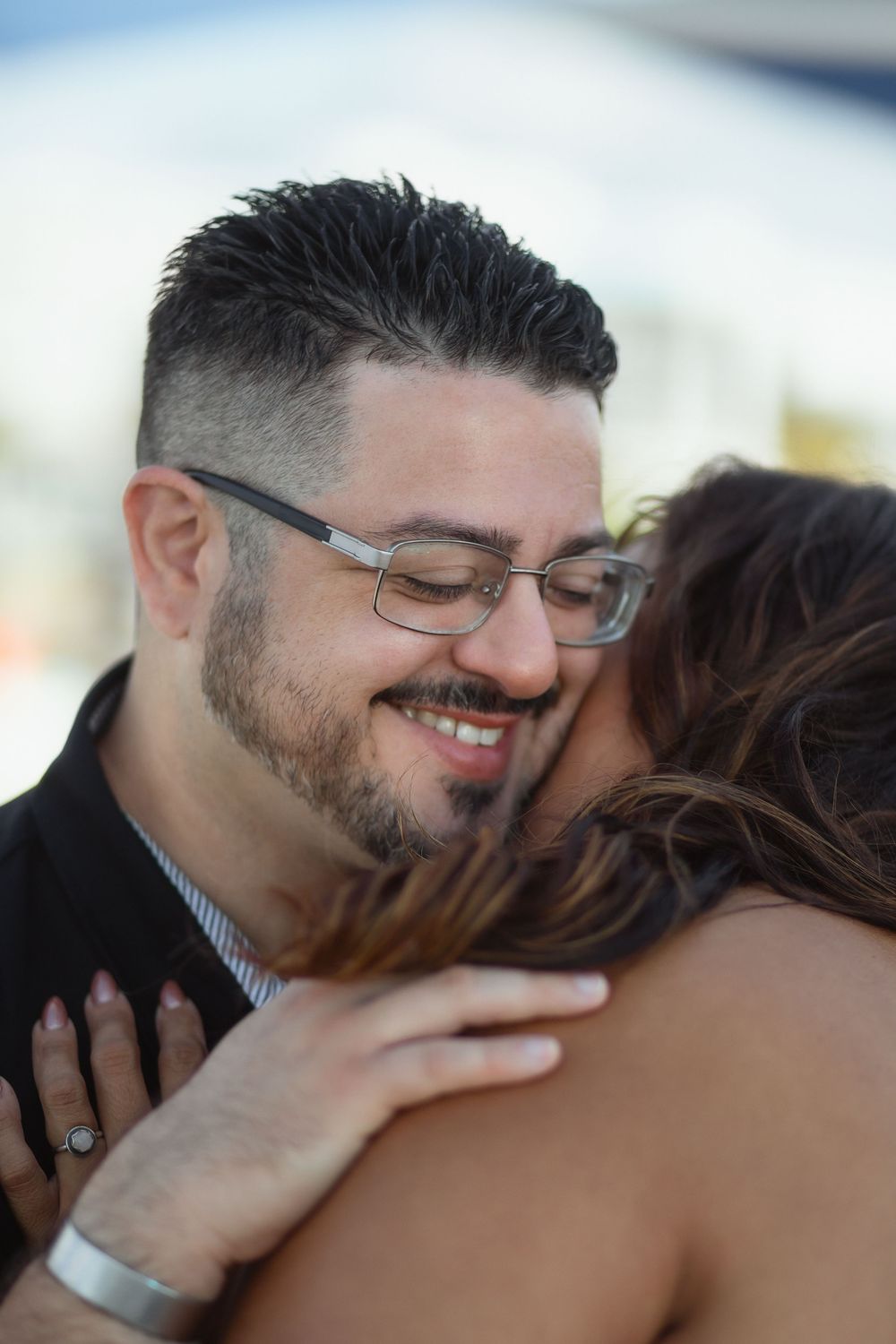Couple hugging at Pompano Beach Pier during engagement couples session.