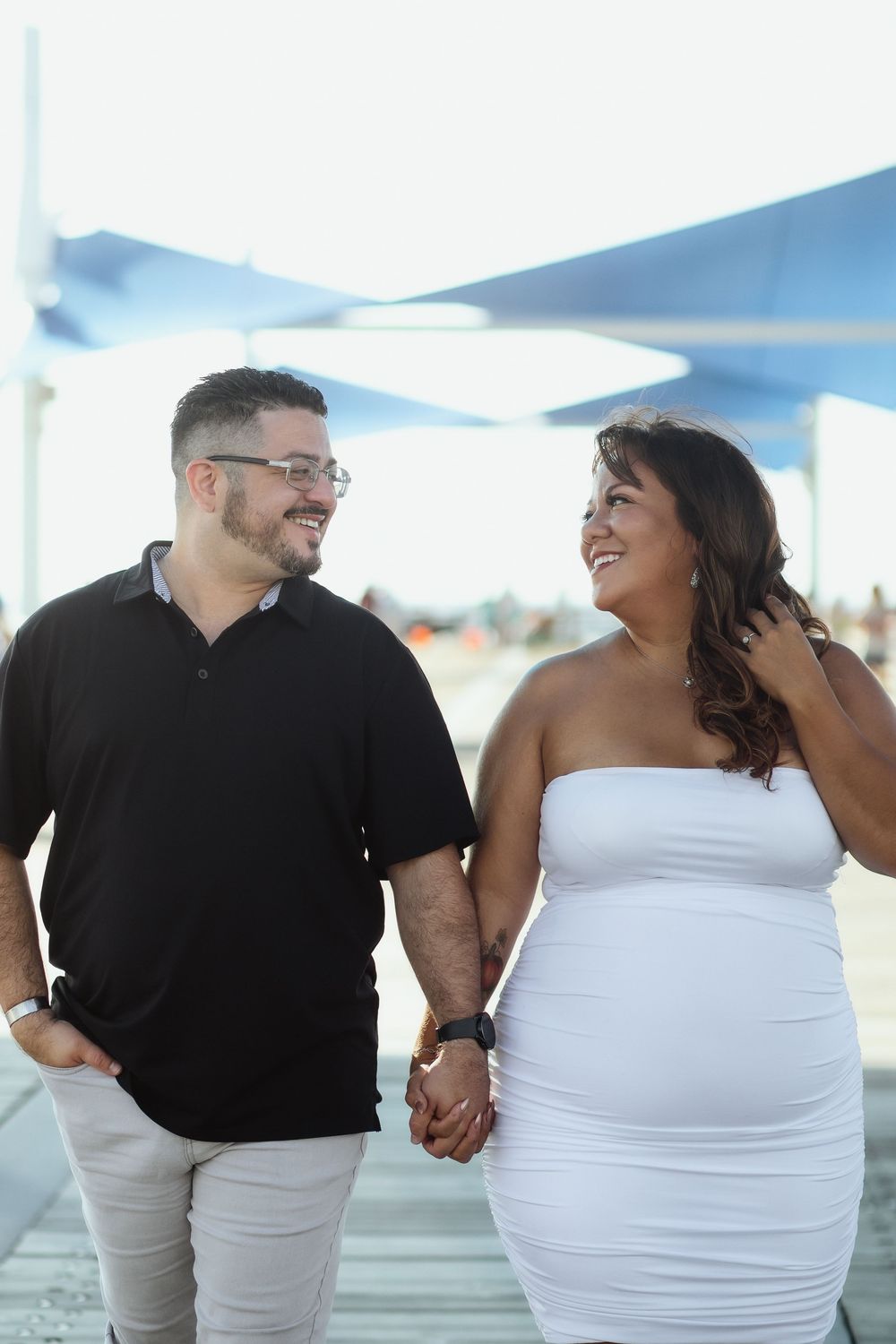Couple walking at Pompano Beach Pier during engagement couples session.