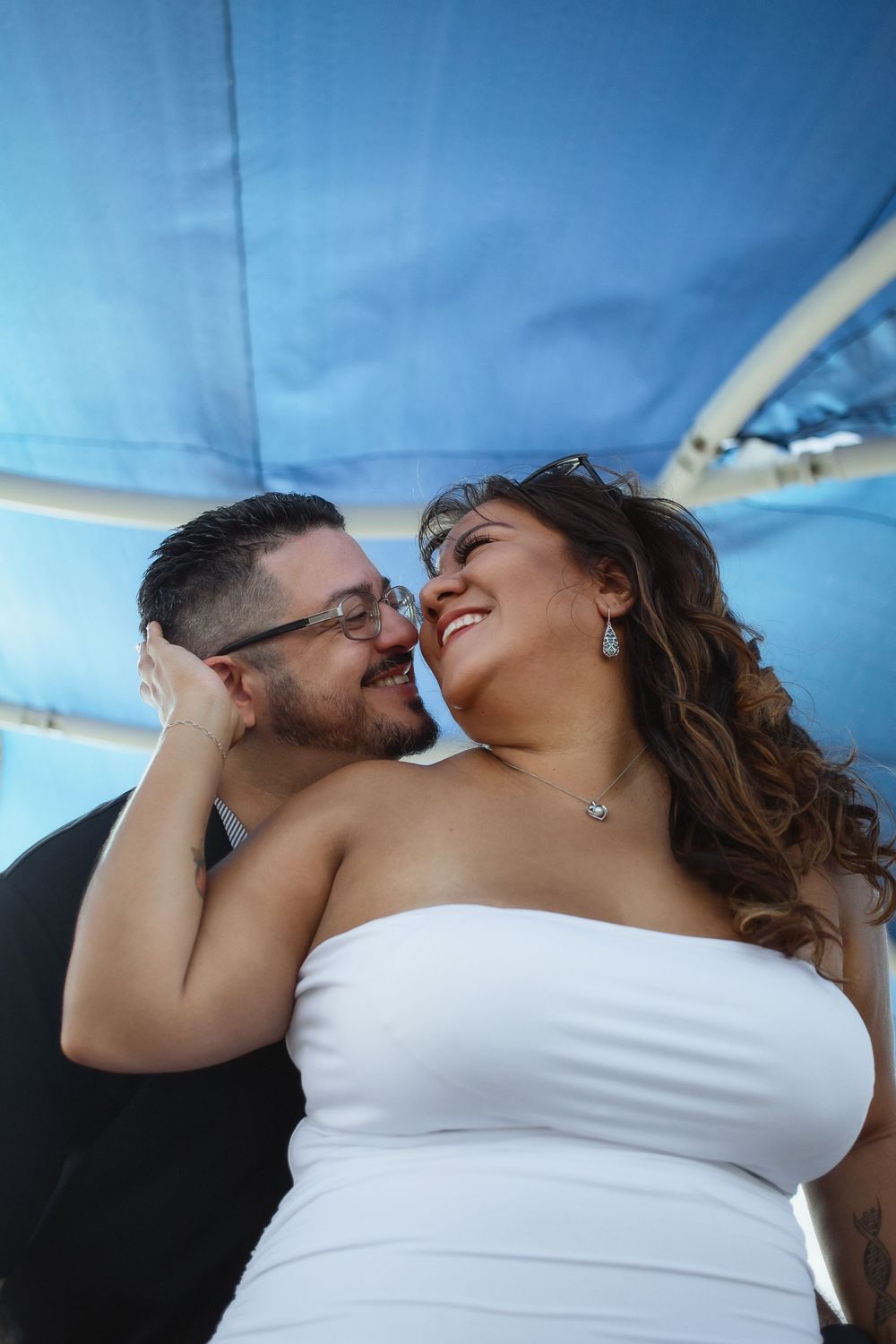 Couple kissing at Pompano Beach Pier during engagement couples session.