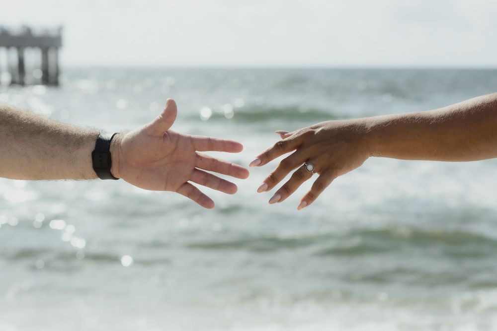 Couple holding hands at Pompano Beach Pier during engagement couples session.
