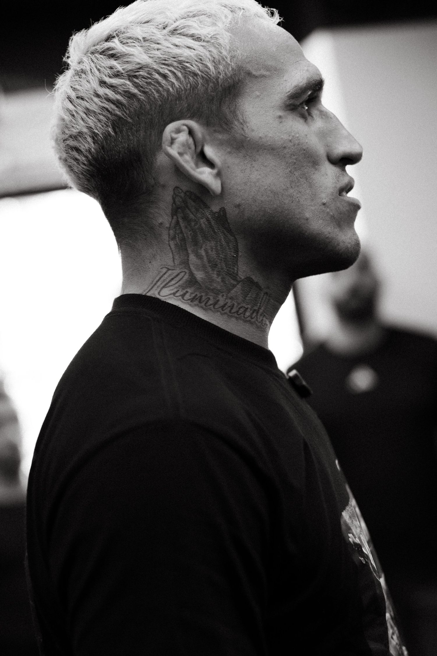 Black and white profile portrait of Charles do Bronx with blonde hair and neck tattoos wearing a black shirt.
