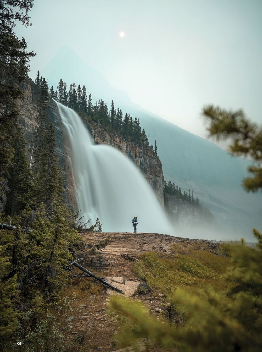 A sequence of scenic waterfall shots in a misty forest landscape shows silhouettes of hikers viewing the majestic cascade.