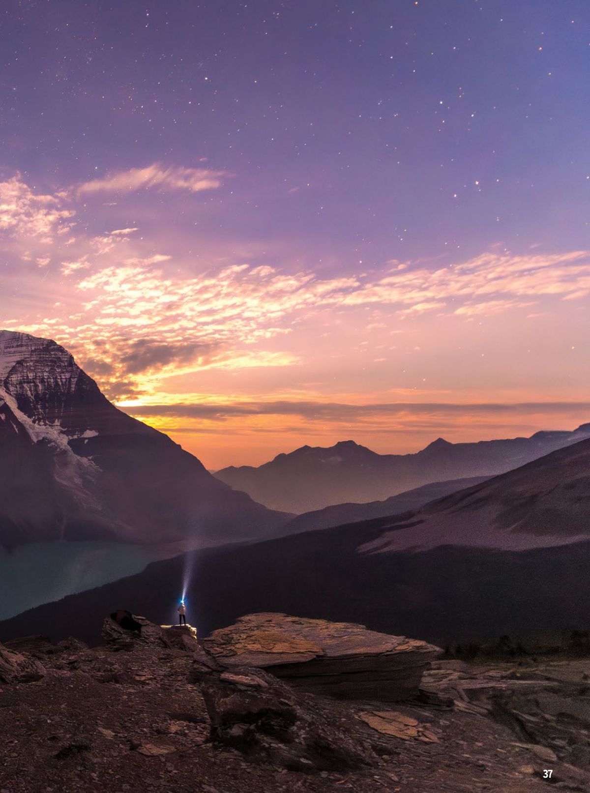 A stunning mountain landscape at sunset with golden clouds and silhouetted peaks in Glacier National Park.