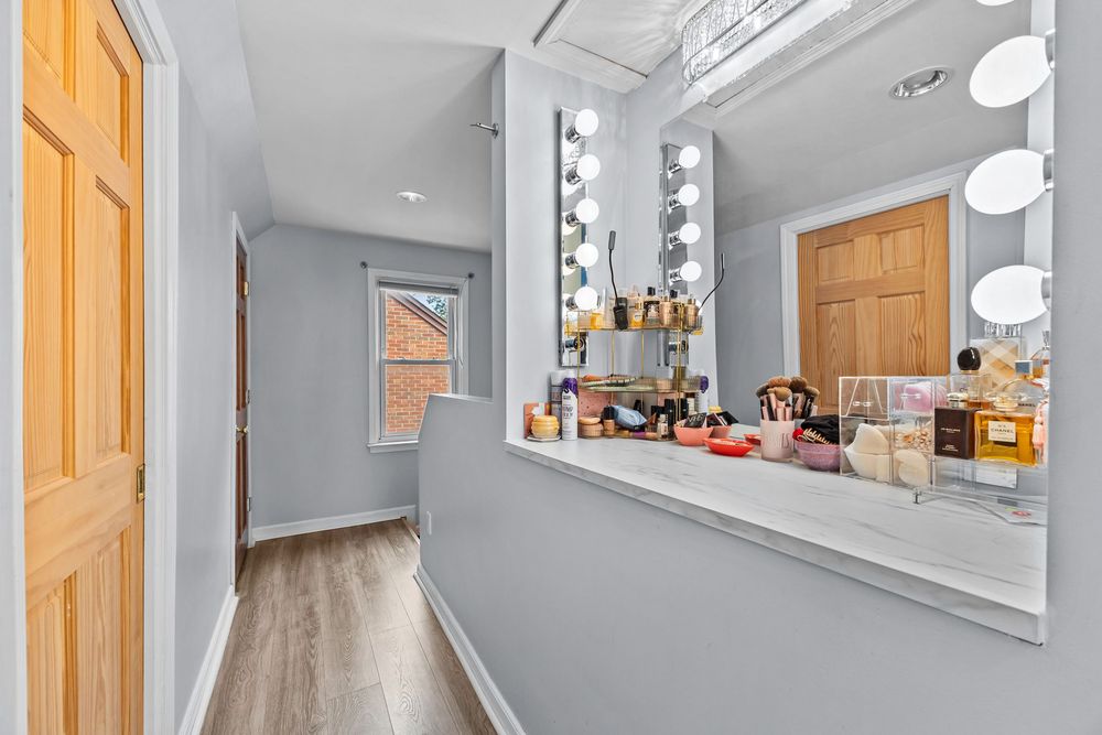 Vanity area with Hollywood-style mirror lights, makeup counter, and wood flooring.