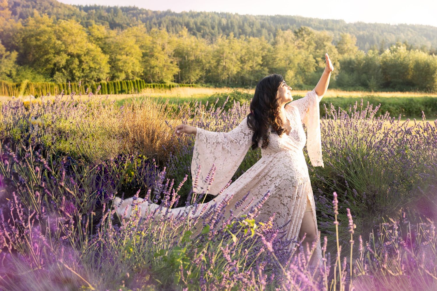 Woman in white lace dress dancing gracefully in a blooming lavender field at golden hour.
