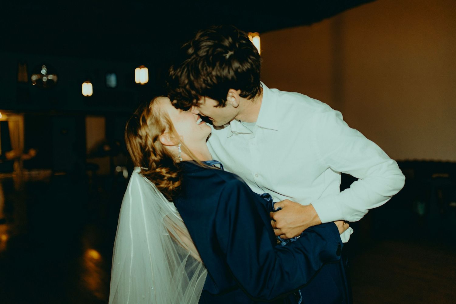 Bride and groom sharing a romantic dip kiss on the dance floor during their wedding reception.