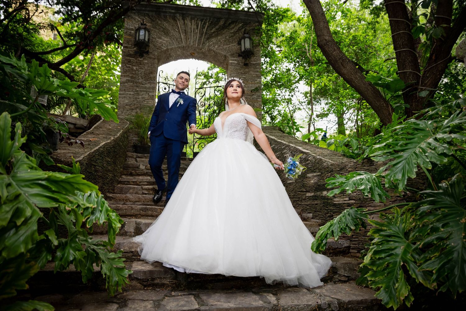 Stone staircase surrounded by lush greenery creates enchanting garden wedding scene.