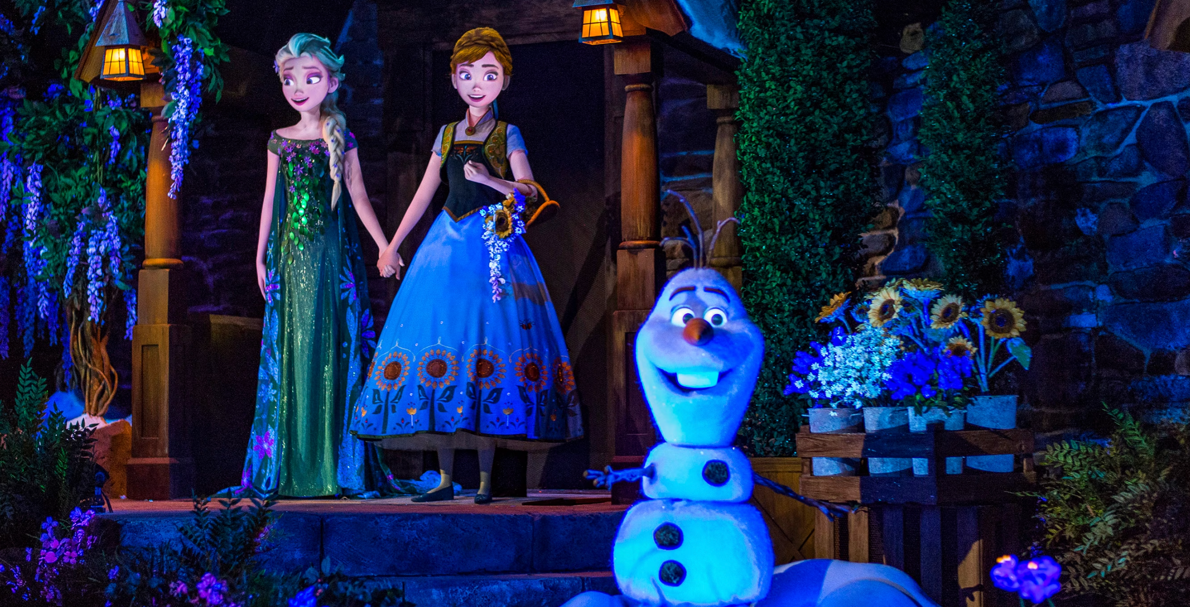 The Olaf meet and greet area at Disney World features glowing blue lights and winter wonderland decor at night.