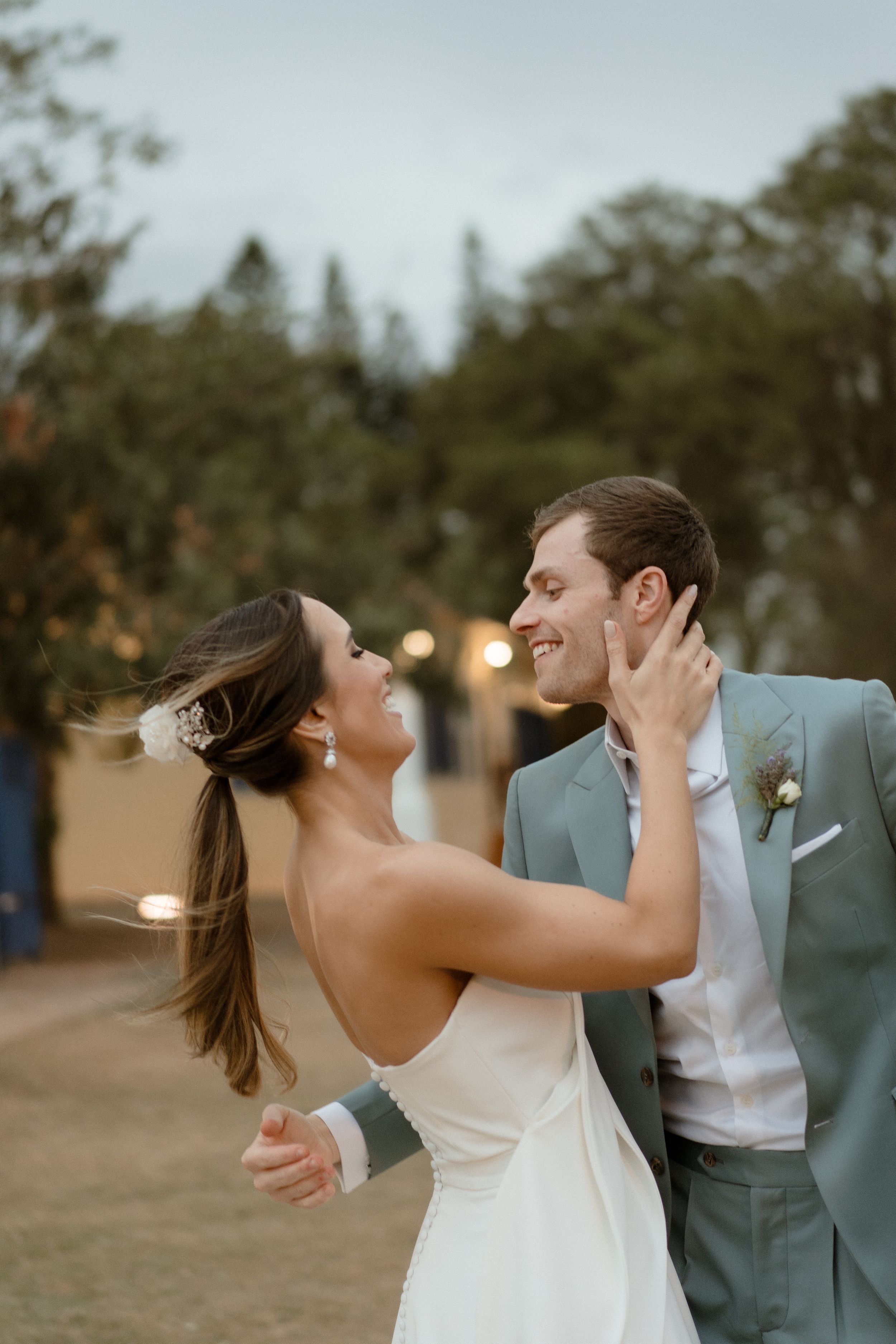 A romantic dance moment captured at sunset with a yellow house and trees in the background.