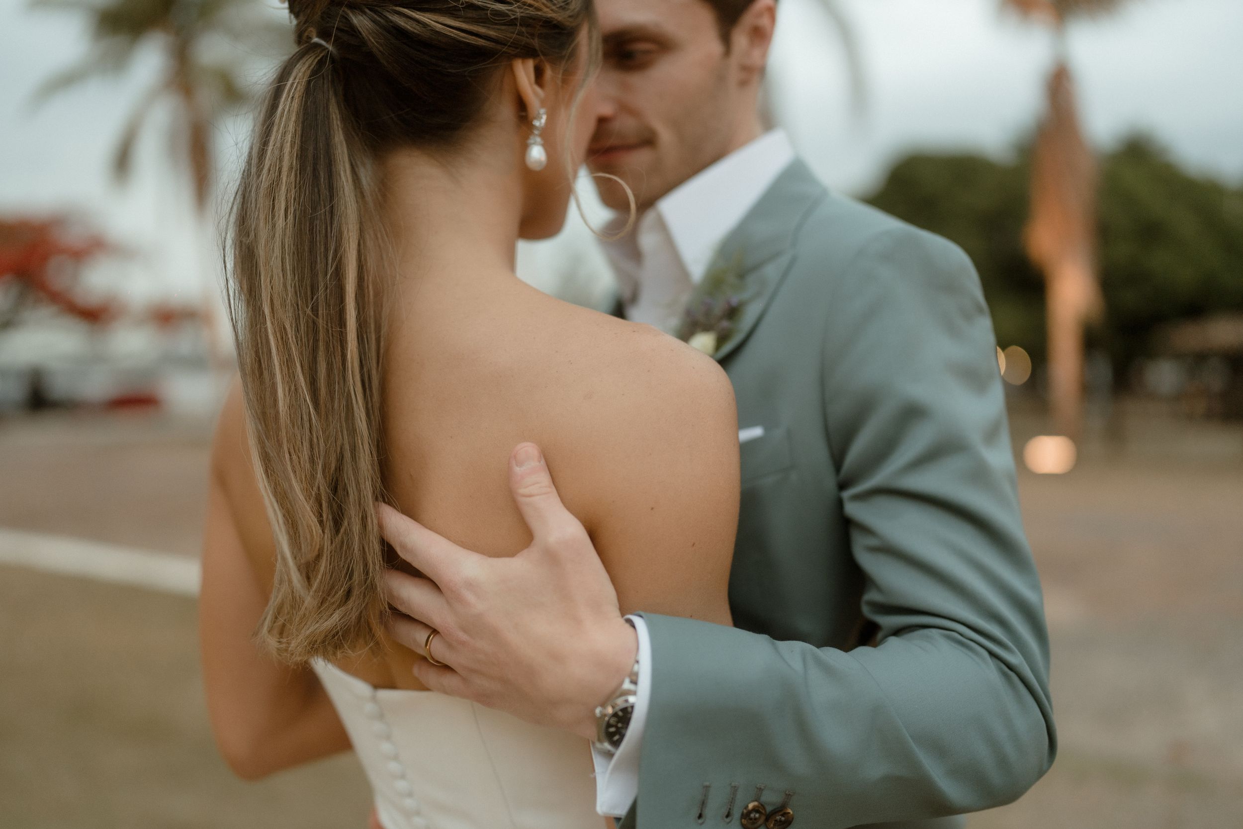 A tender embrace captured in warm evening light during an outdoor wedding celebration.