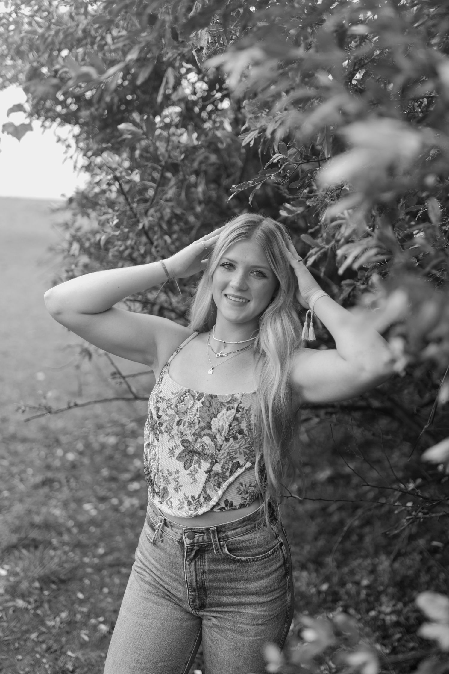 Black and white portrait in a garden setting showcasing a floral top and classic denim style. Virginia graduation/senior session.
