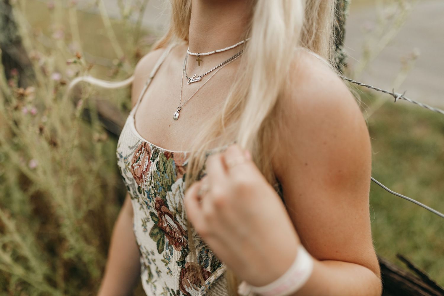 Close-up detail of layered necklaces and floral corset top in natural lighting. Virginia graduation/senior session.