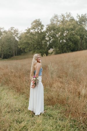 Ethereal portrait in flowing white dress holding bouquet in golden autumn field. Virginia graduation/senior session.