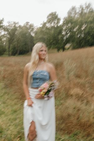 Artistic motion blur portrait in denim and white dress holding fresh flowers. Virginia graduation/senior session.