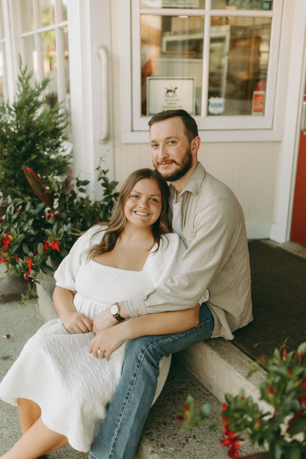 Sweet couple posing together on porch with decorative plants and red flowers. Floyd, VA