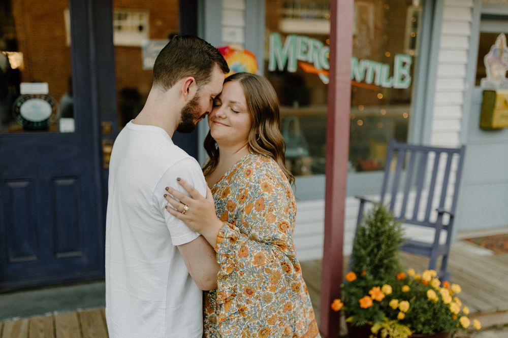 Intimate moment between couple in casual attire standing outside a shop with flowers. Floyd, VA