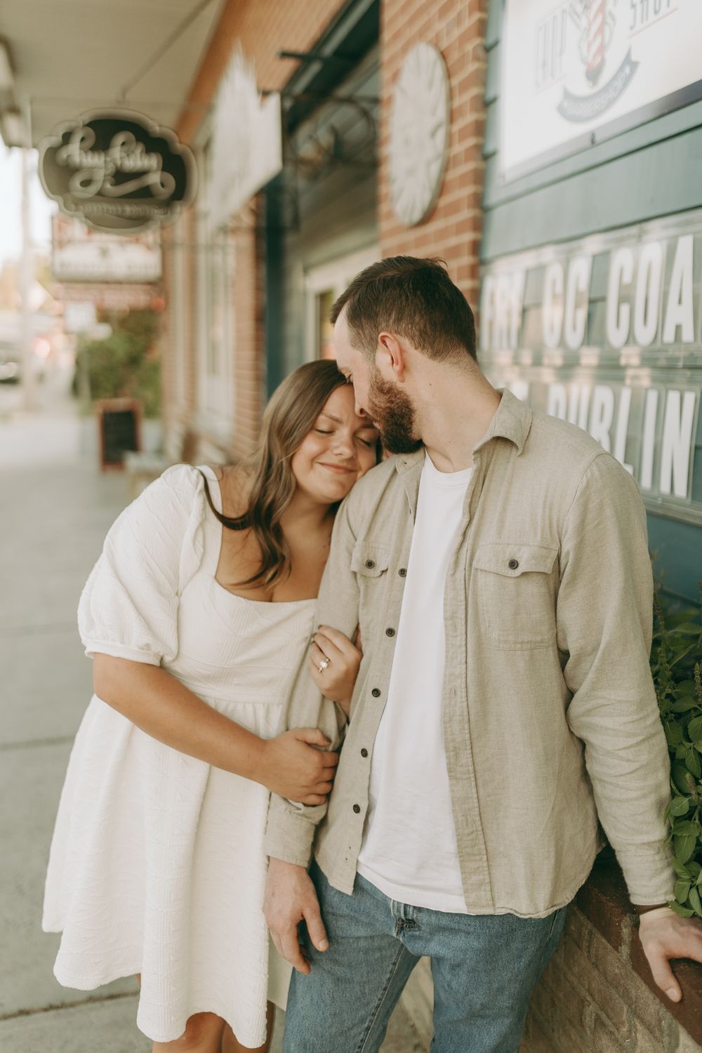 A couple shares an intimate moment while standing outside a brick storefront. Floyd, VA