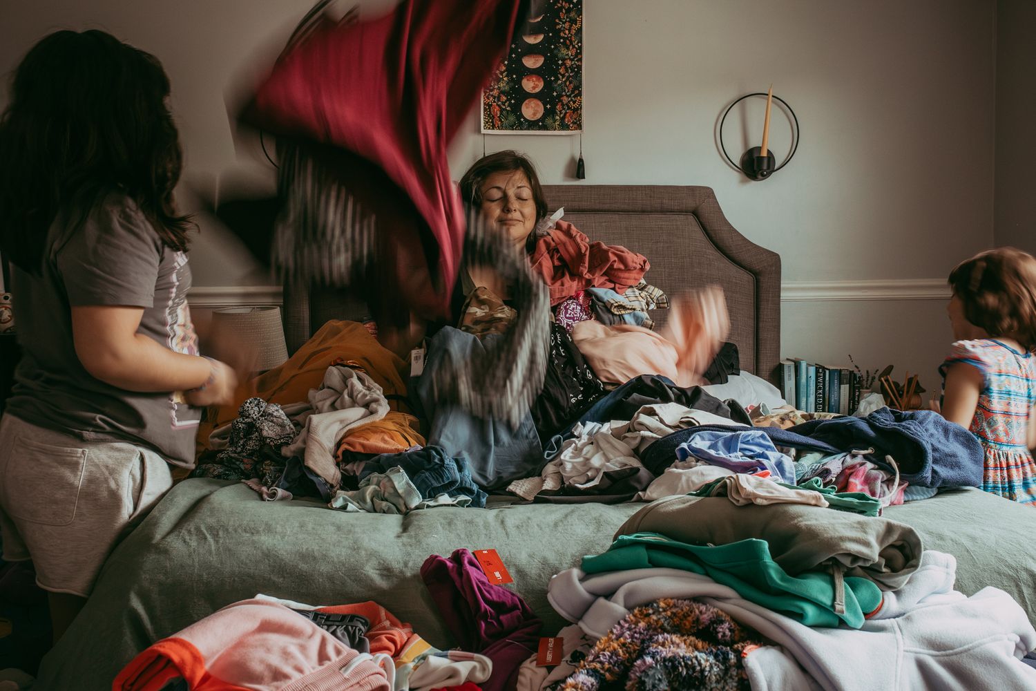 Family having fun and playing together, tossing clothes and laundry on a messy bed in a bedroom. Whitney Popp, Virginia.