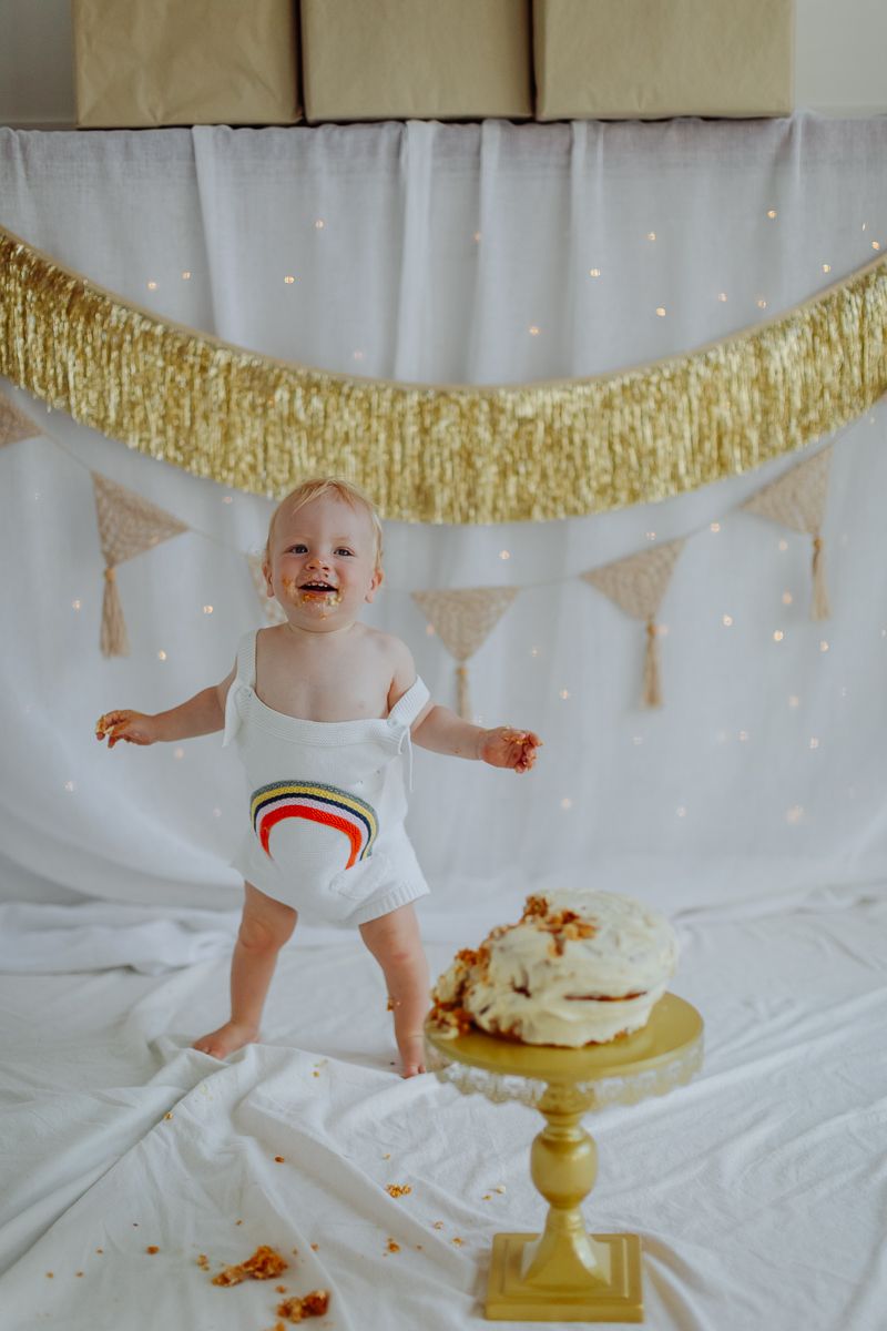 1 year old boy standing and smiling cake smash mini photoshoot