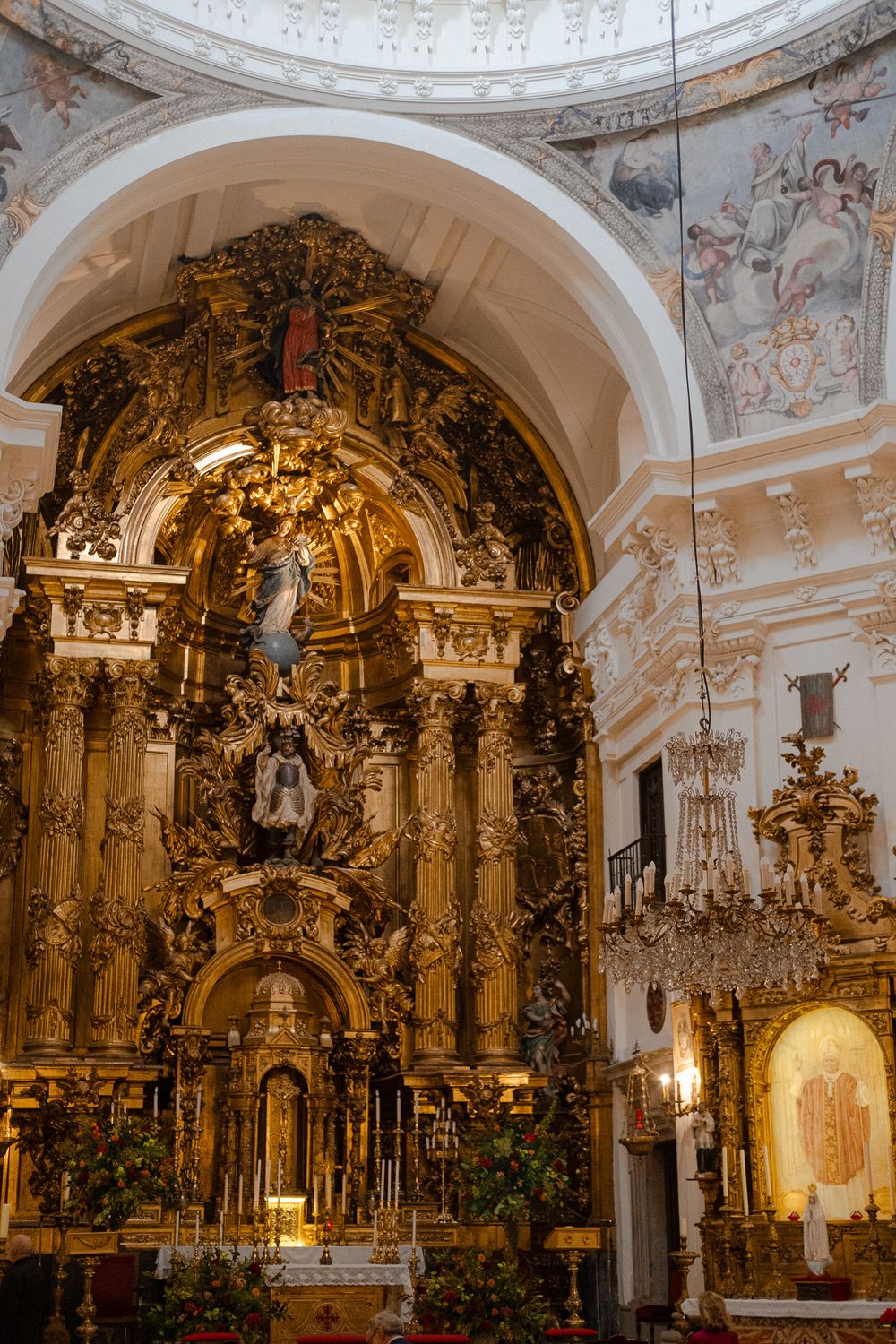 Ornate gold baroque altar in a Catholic church with elaborate decorations and religious statues.