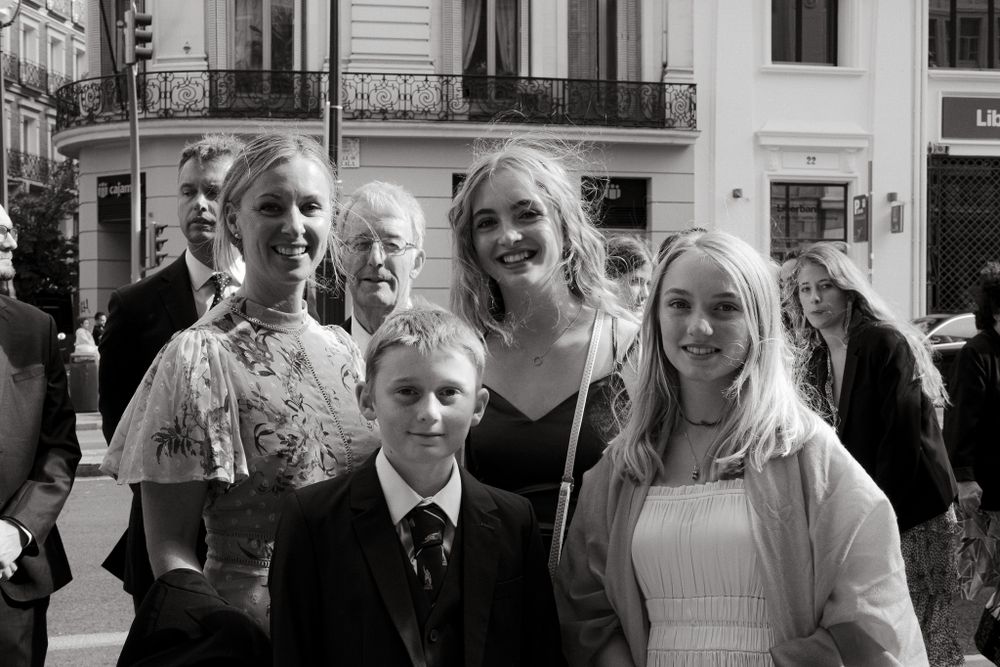 A group poses together on a city street in formal attire during what appears to be a special occasion.