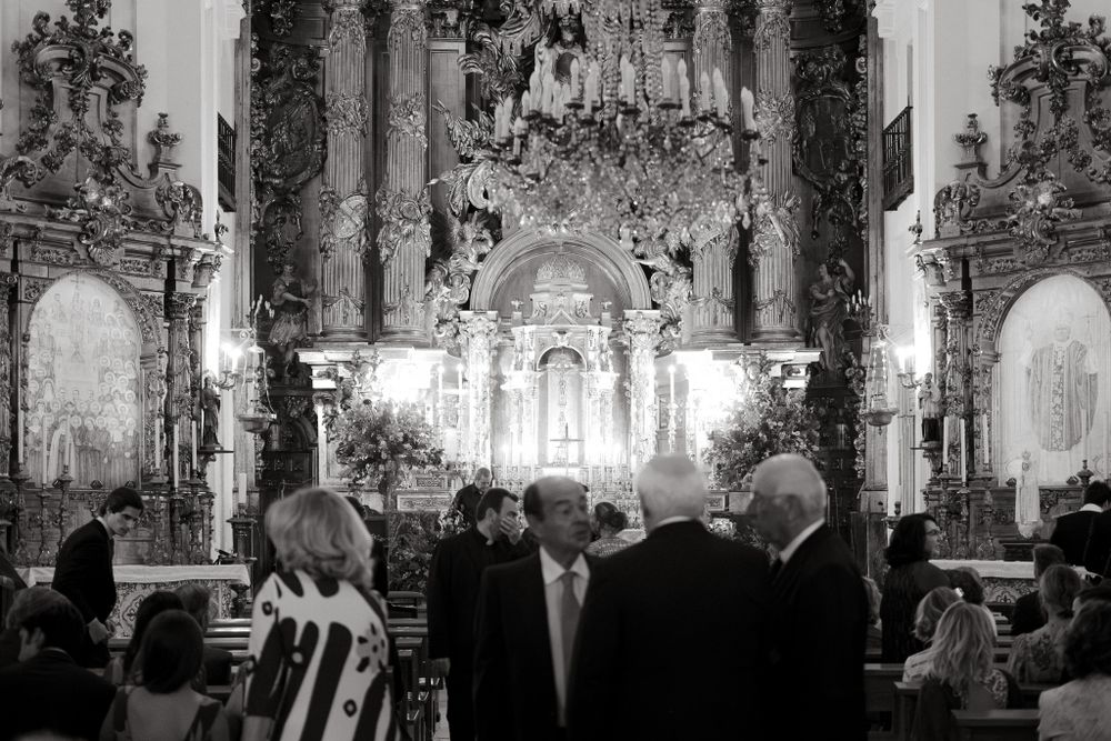 Interior of an ornate church with people gathered for a ceremony beneath elaborate baroque decorations.