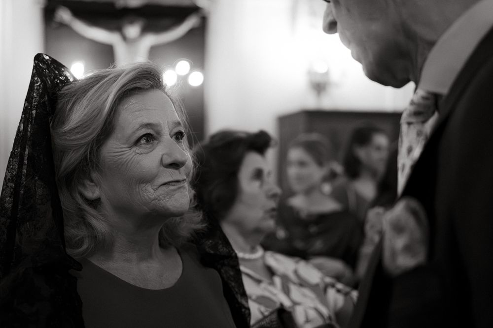 A black and white interior shot showing guests in formal attire during a church event.
