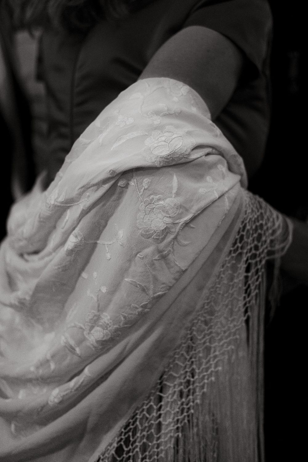 Close-up detail of intricate white lace and fabric from a formal garment.