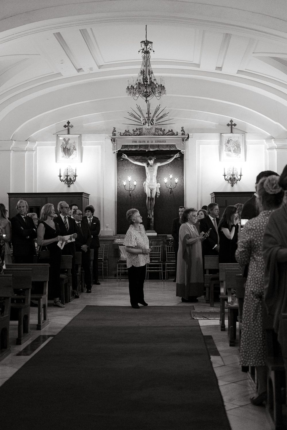 Interior of an ornate church with chandelier and crucifix during a formal gathering.