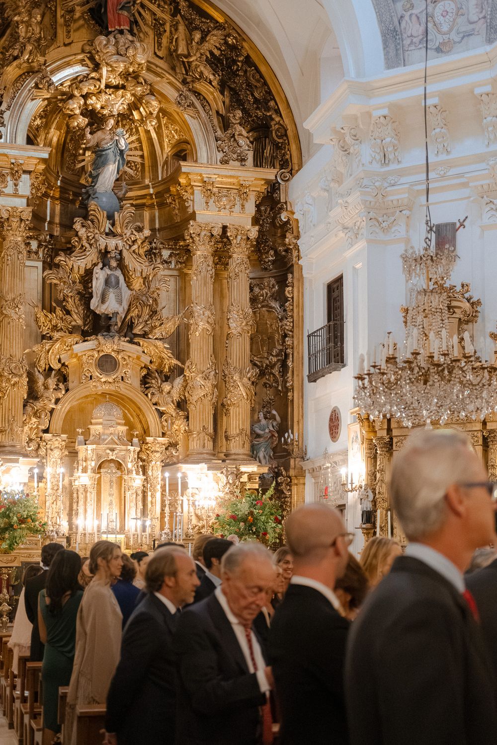 Ornate baroque church interior with golden altar and gathered congregation.