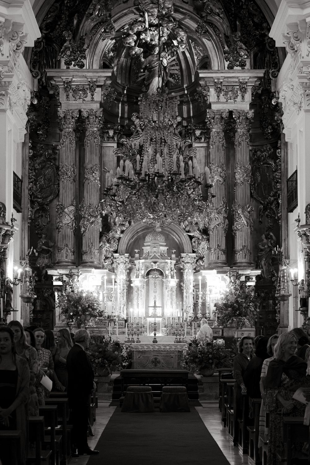 Elaborate baroque church interior with detailed gilded architecture and standing congregation.