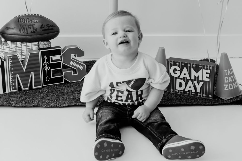 Football themed baby photoshoot with decor and signs spelling out 'GAME DAY'.