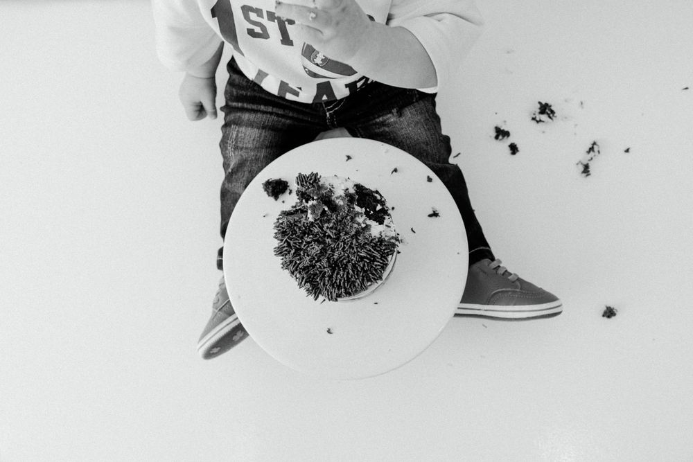 Black and white overhead view of smashed birthday cake with crumbs scattered.