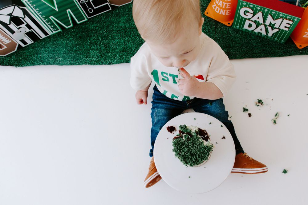 Overhead view of food plate on white surface with green banner and birthday party decor.